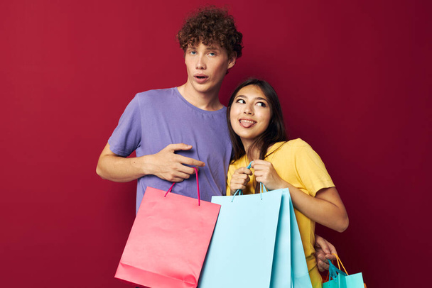 young boy and girl in colorful T-shirts with bags Shopping isolated background unaltered - Фото, изображение