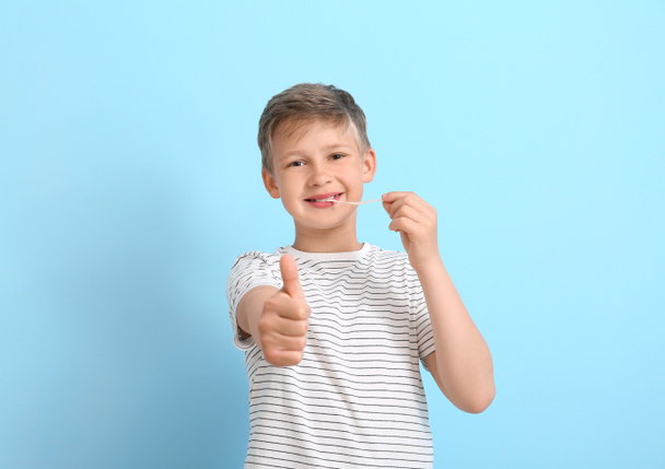 Little boy with chewing gum showing thumb-up on blue background - Fotó, kép