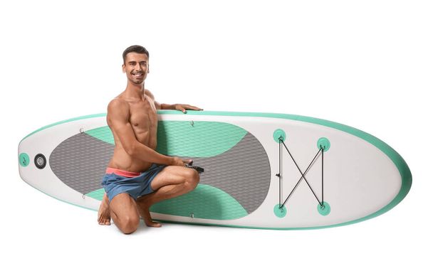 Schöner junger Mann mit Brett zum Surfen auf weißem Hintergrund - Foto, Bild