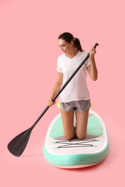 Young woman with board for sup surfing and oar on color background - Φωτογραφία, εικόνα