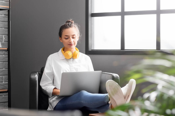 Pretty young woman with laptop and headphones at home - Fotó, kép