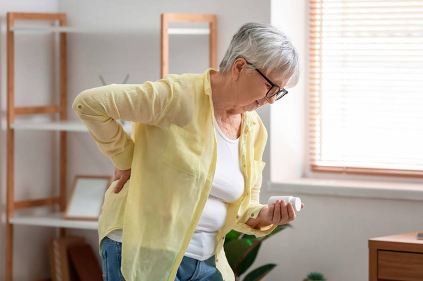 Senior woman with pills suffering from back pain at home - Foto, immagini
