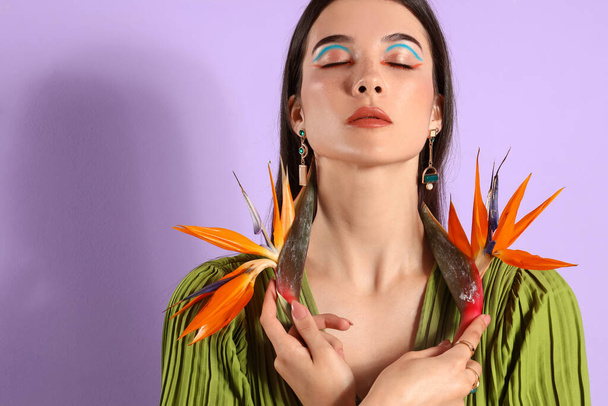 Beautiful young woman with strelitzia flowers on color background - Photo, Image