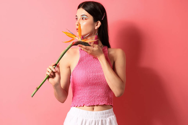 Beautiful young woman with strelitzia flower on color background - 写真・画像