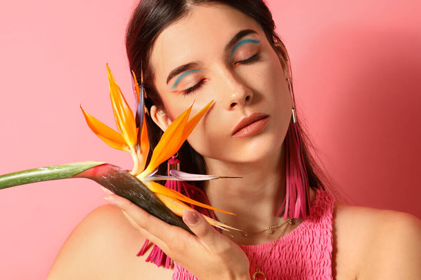 Hermosa mujer joven con flor strelitzia sobre fondo de color - Foto, imagen