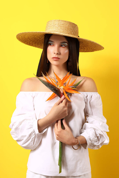 Beautiful young woman with strelitzia flowers on color background - Foto, Imagem