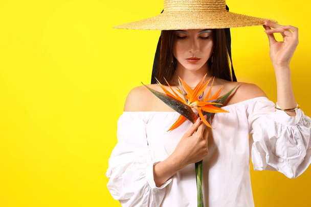 Beautiful young woman with strelitzia flowers on color background - 写真・画像