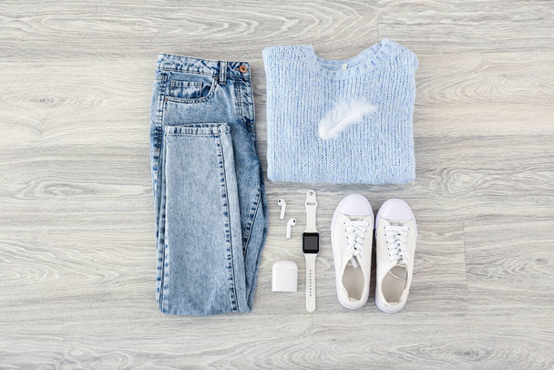 Elegante ropa femenina, zapatos, auriculares y smartwatch sobre fondo de madera gris - Foto, imagen