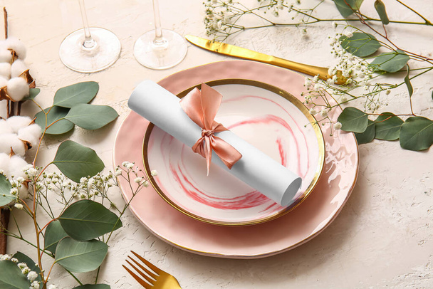 Beautiful table setting with wedding invitation on light background - Photo, Image