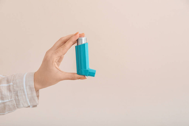 Woman holding asthma inhaler on beige background - Фото, изображение