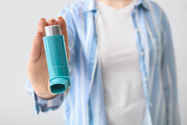 Woman holding asthma inhaler on light background, closeup - Фото, изображение