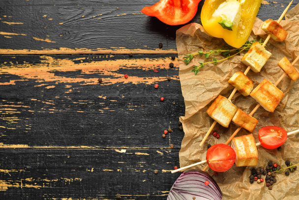 Parchment with grilled tofu cheese skewers and vegetables on dark wooden background - Foto, Bild