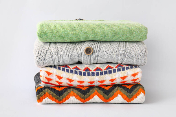 Stack of different sweaters on grey background - Foto, immagini