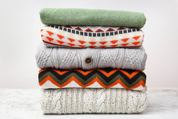 Stack of stylish sweaters on table against light background - Fotó, kép