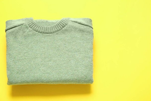 Stylish folded sweater on yellow background - 写真・画像