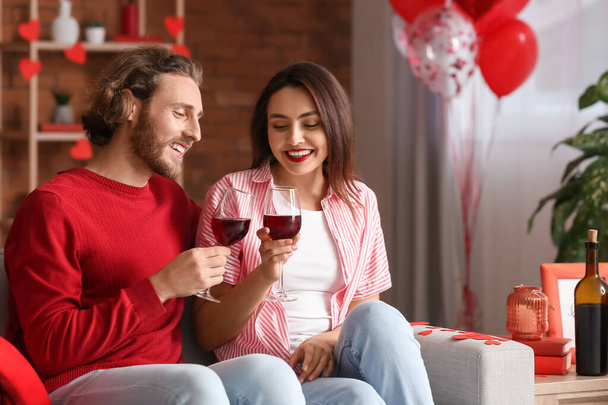 Ευτυχισμένο νεαρό ζευγάρι πίνοντας κρασί στο σπίτι του Αγίου Βαλεντίνου - Φωτογραφία, εικόνα