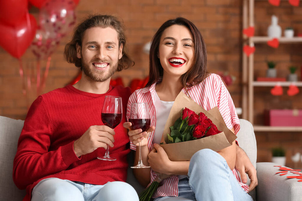 バレンタインデーに家でワインを飲む幸せな若いカップル - 写真・画像