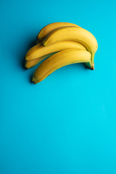 fresh ripe bananas on blue background - Foto, afbeelding