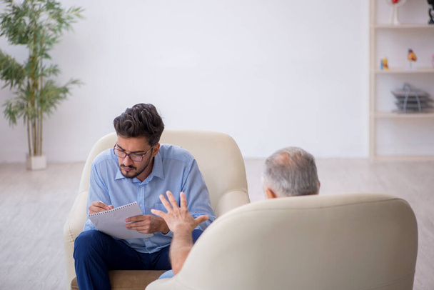 Alter Mann besucht jungen männlichen Psychotherapeuten - Foto, Bild