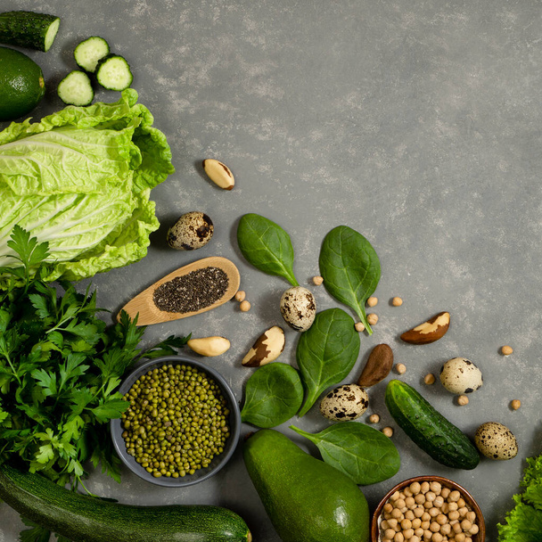Cadre végétal avec légumes verts, courgettes, avocats et haricots avec noix sur fond gris pour menu ou liste de produits utiles - Photo, image