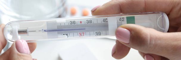 Female hands thermometer on table glass of water and PCR test - Photo, Image
