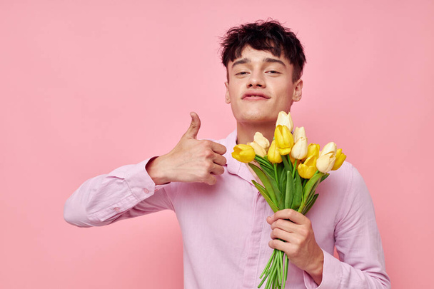 portrait of a young man Bouquet of yellow flowers romance posing fashion pink background unaltered - Φωτογραφία, εικόνα