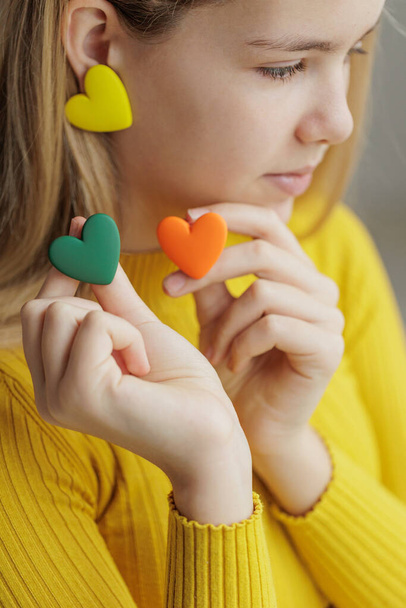 Teenage girl chooses jewelry earrings. Heart shaped earrings. St. Valentines Day. - Foto, imagen