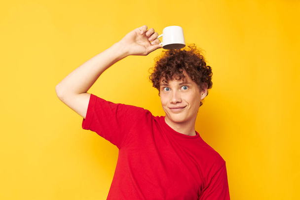 Young curly-haired man posing with a white mug and in the hands of a drink Lifestyle unaltered - Фото, зображення