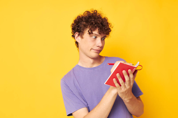 portrait of a young curly man notepad with pen learning emotions isolated background unaltered - Foto, Imagem