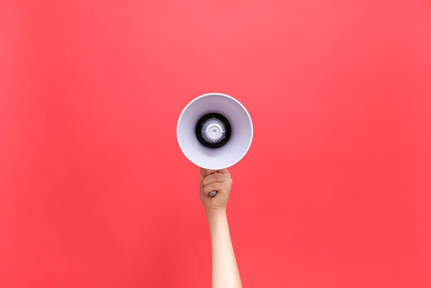 Close up of female hand holding bullhorn public address megaphone, hot news announce discounts sale hurry up communication concept, isolated on pastel red background studio with copy space mock up - Foto, Imagem