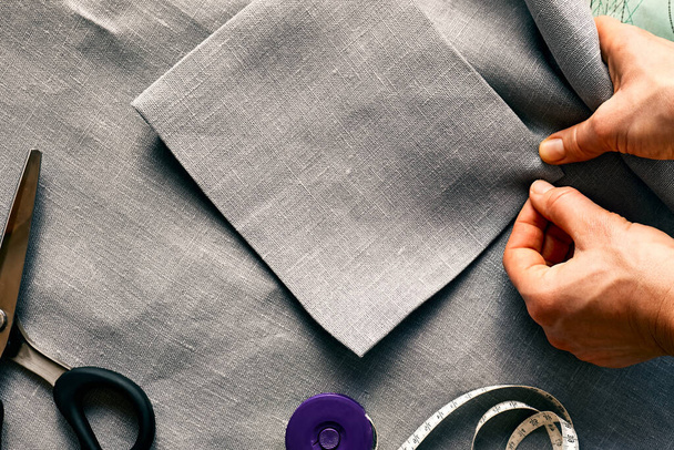 Woman is sketching pattern on a linen fabric Seamstress basting and sewing in a small studio Sartorial clothers Fashion studio, ραπτική, χειροποίητη ενδυμασία έννοια Αργή μόδα Συνείδηση κατανάλωση - Φωτογραφία, εικόνα