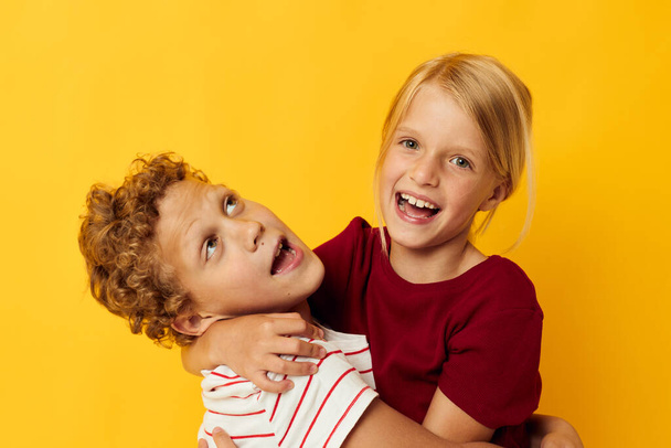 Portrait of cute children standing side by side posing childhood emotions yellow background - Foto, imagen