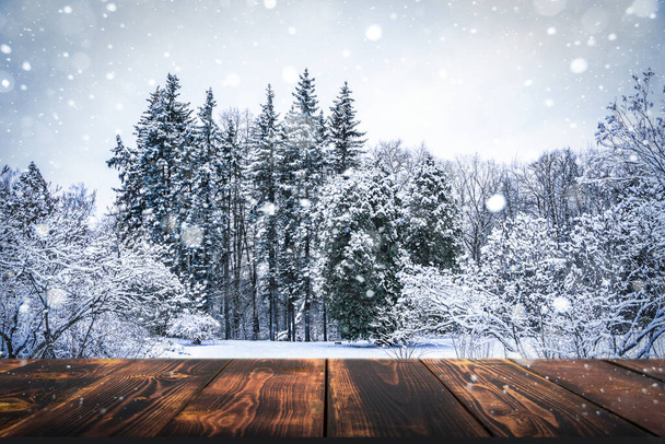 Зимовий ліс з дерев'яним столовим фоном. Розмитий сніговий пейзаж і порожній сільський стіл для продуктів або товарів
. - Фото, зображення