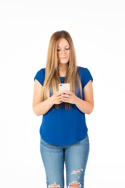 Молода жінка на білому тлі дивиться на смартфон
. - Фото, зображення
