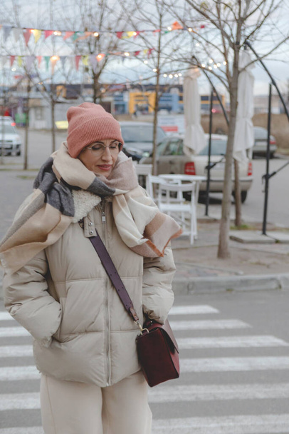 Beautiful baby boomer woman of middle age in glasses and stylish casual clothes on the street. - Fotó, kép