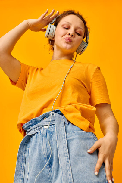 pretty woman grimace headphones music technology yellow background unaltered - Foto, Imagen