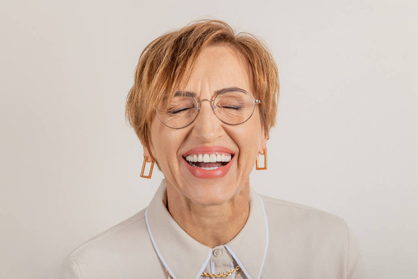  Middle-aged baby boomer woman smiles broadly with beautiful healthy teeth. - Foto, afbeelding