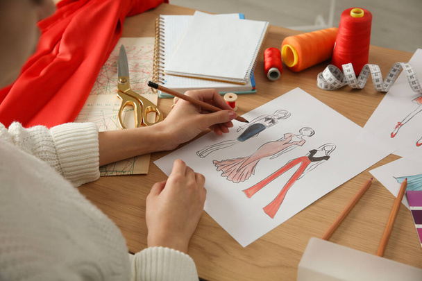 Fashion designer creating new clothes in sketchbook at wooden table, closeup - Fotó, kép
