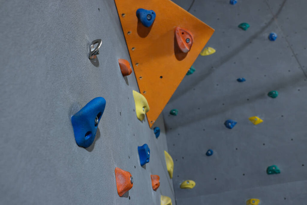 Climbing wall with holds in gym, low angle view. Extreme sport - Fotó, kép