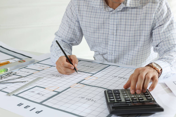 Architect working with construction drawings and calculator indoors, closeup - Foto, Imagem