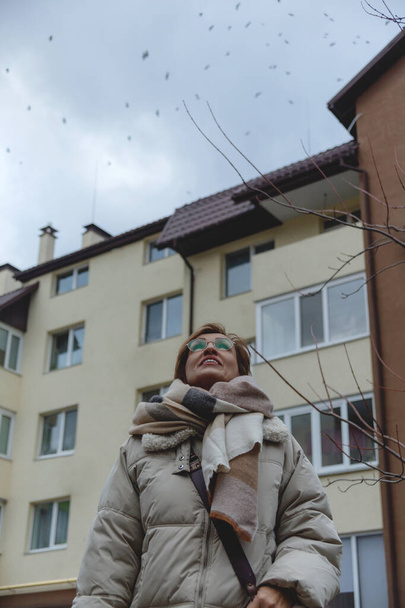 Beautiful baby boomer woman of middle age in glasses and stylish casual clothes looks at the sky. - Foto, Bild
