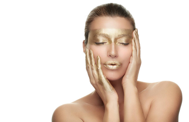 Gold based anti aging skincare concept. Beautiful model woman with gold treatment posing with closed eyes and a serene expression. Close up beauty portrait on white - Foto, Imagem