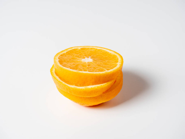 Крупним планом оранжевий нарізаний скибочками лежить на білому тлі. Смачні красиві фрукти, повні вітамінів. Студійний знімок
 - Фото, зображення