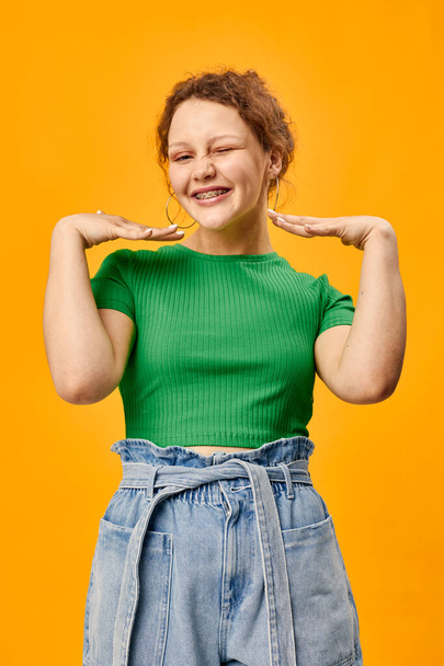 cheerful cute girl with earrings green t-shirts yellow background - 写真・画像