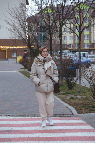 Beautiful baby boomer woman of middle age in stylish casual clothes crosses road. - Fotoğraf, Görsel