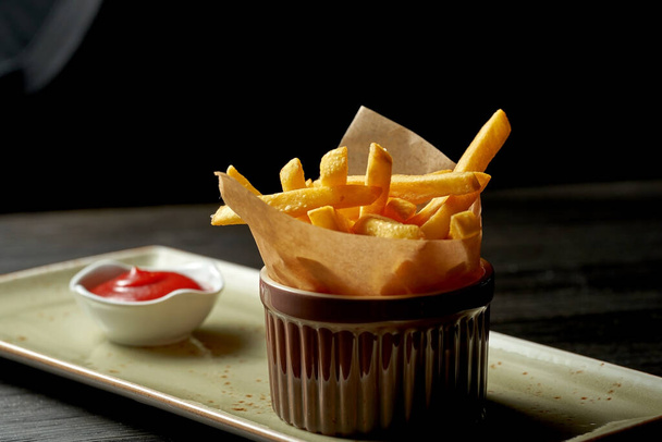 Classic side dish - French fries with beautiful serving on a plate with red sauce - Фото, изображение