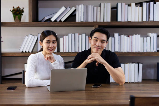 Happy Asian young Businesswoman and Business man working laptop computer on wood desk in Home office - 写真・画像