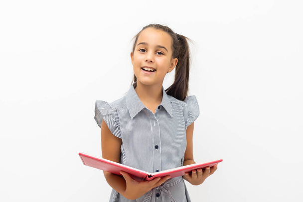 klein meisje geïsoleerd in wit holding schoolboek - Foto, afbeelding
