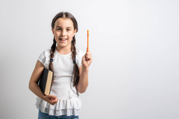 Kluges kleines Schulmädchen mit Stift und Büchern, das in einem Klassenzimmer einen Test schreibt. Kind in einer Grundschule. Bildung und Lernen für Kinder. - Foto, Bild