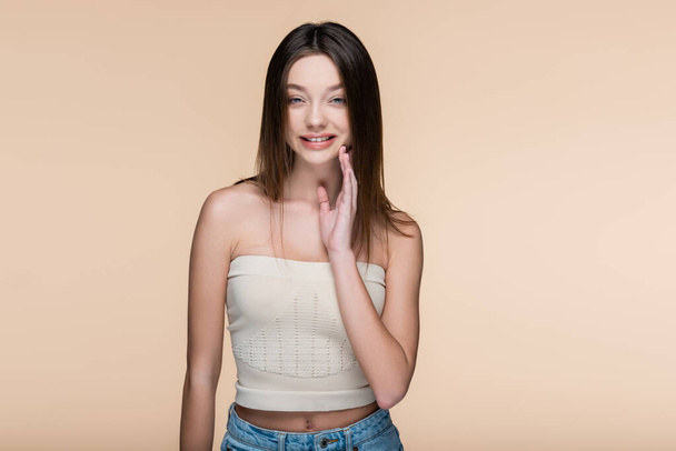 happy young woman in crop top with bare shoulders isolated on beige - Foto, Imagem
